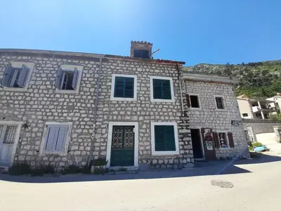 a stone building with green shutters on it at Beach edge 4-Bed House in Muo Kotor in Kotor