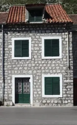 a stone building with green doors and a red roof at Beach edge 4-Bed House in Muo Kotor in Kotor