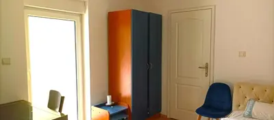 a living room with a blue chair and a cabinet at 2-level apartment with terraces by the sea in Budva