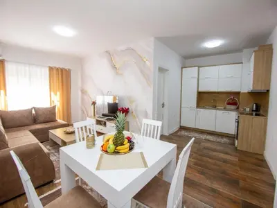 a kitchen and living room with a white table and chairs at Apartment Ochsen in Ulcinj