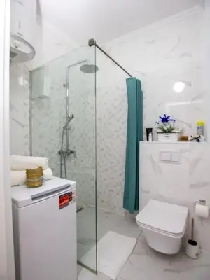 a white bathroom with a shower and a toilet at Apartment Ochsen in Ulcinj