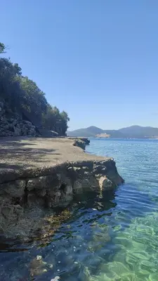 a rocky shoreline with the ocean in the background at Apartman u sumi nedaleko od mora in Bigovo