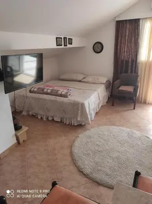 a bedroom with a bed and a flat screen tv at Apartman u sumi nedaleko od mora in Bigovo