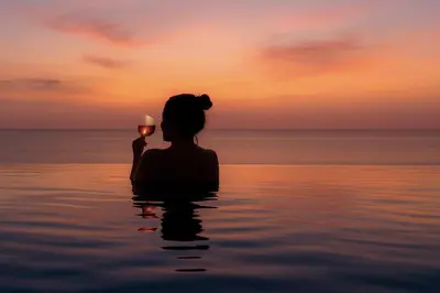 a woman sitting in the water holding a wine glass at Hotel Ponta Plaza Conference & Spa in Budva