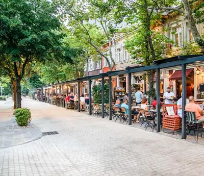 a group of people sitting at tables outside a restaurant at Gallery apartment in Podgorica