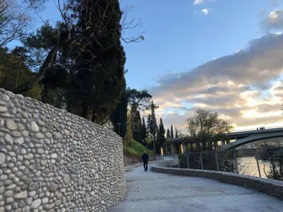 a man walking down a sidewalk next to a stone wall at Gallery apartment in Podgorica
