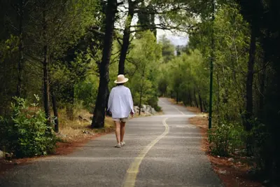 a person walking down a road with a hat at Gallery apartment in Podgorica