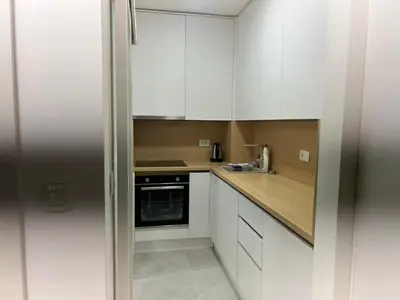 a white kitchen with white cabinets and a sink at Studio apartman Vivo Central in Podgorica