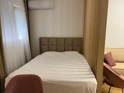 a small bedroom with a bed and a chair at Studio apartman Vivo Central in Podgorica