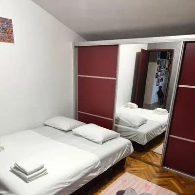 two beds in a small room with a mirror at Vila Marija in Podgorica