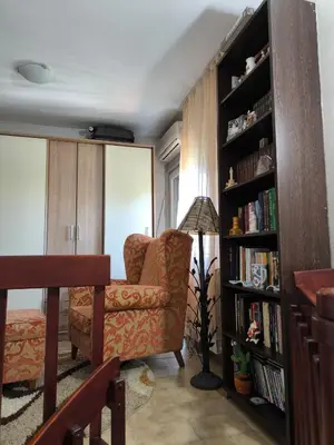 a living room with a chair and a book shelf at Vila Marija in Podgorica