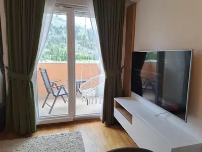 a living room with a television and a balcony at Marina City key Luxury Studio in Podgorica