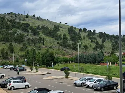 a parking lot with cars parked in front of a hill at Marina City key Luxury Studio in Podgorica