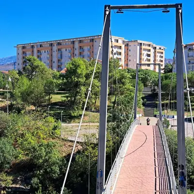 a person crosses a suspension bridge in a city at Marina City key Luxury Studio in Podgorica