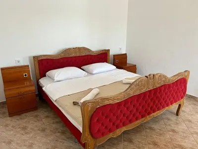 a bedroom with a wooden bed with a red headboard at Sunny Terraces in Cetinje