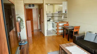 a living room with a couch and a table and a kitchen at Modern Apartment in City Center in Podgorica