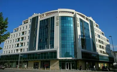 a large building with glass windows on a street at Modern Apartment in City Center in Podgorica
