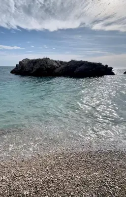 a rock in the water next to a beach at Nicks sea view apartment I in Bar