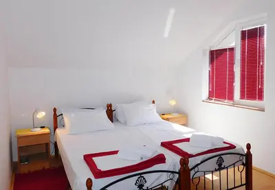 a bedroom with a large white bed with red accents at Villa Jovana Sea View in Budva