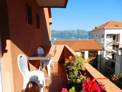 a balcony with two white chairs and a table and flowers at Villa Jovana Sea View in Budva