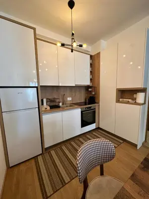 a kitchen with white cabinets and a chair at Apartman Diplomat in Budva