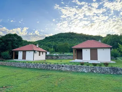 two small buildings in a field with a stone wall at Paradise Valley in Rvaši