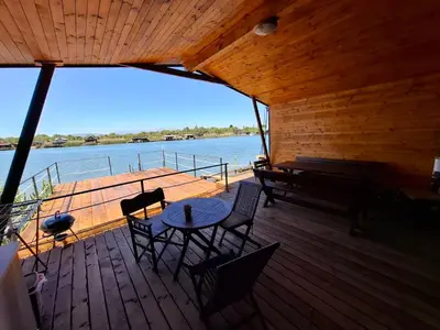 a wooden deck with a table and chairs and a piano at Ada Bojana kucica Una in Ulcinj