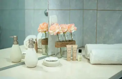 a bathroom counter with pink flowers in a mirror at Apartment Pavle near the center with a view in Kotor