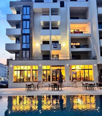 a building with tables and chairs in front of a pool at Cataleya Resort in Ulcinj