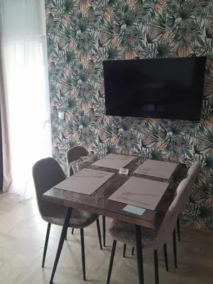 a dining room table with chairs and a tv at Apartmani Radmanovic in Tivat