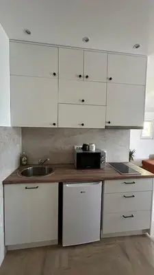 a kitchen with white cabinets and a sink at Apartmani Radmanovic in Tivat