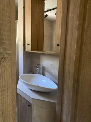 a bathroom with a white sink and a wooden cabinet at Apartmani Radmanovic in Tivat