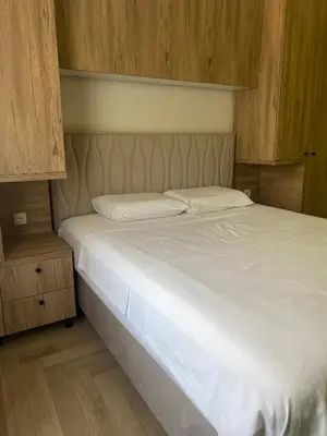 a bedroom with a bed with white sheets and wooden walls at Apartmani Radmanovic in Tivat