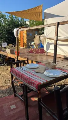 a picnic table with plates on it on a deck at Tranquil Tent Retreat Glamping in Zaljevo