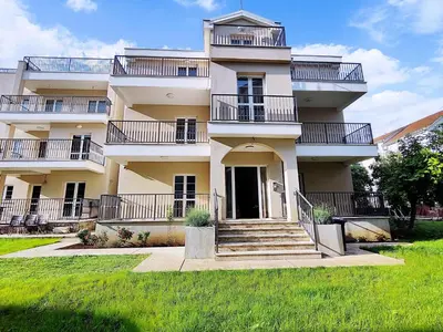 a large white building with stairs in a yard at Bofani Apartments Budva in Budva