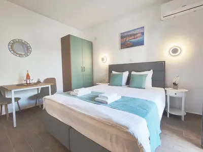 a bedroom with a bed with a desk and a table at Bofani Apartments Budva in Budva