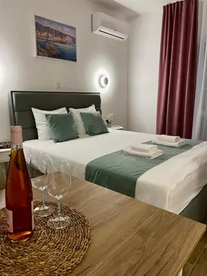 a bedroom with a bed with a bottle and glasses on a table at Bofani Apartments Budva in Budva