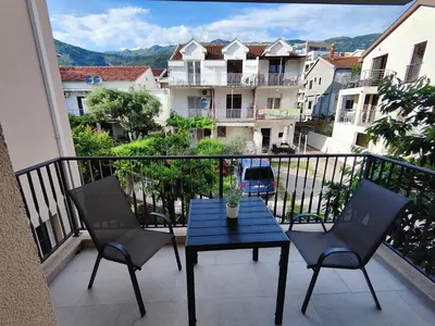 a balcony with a blue table and chairs and buildings at Bofani Apartments Budva in Budva