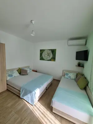 two beds in a room with white walls and wooden floors at DMD Apartments in Budva