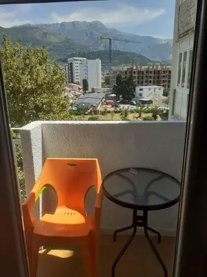 an orange chair and a glass table on a balcony at Lamela in Bar