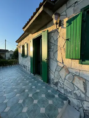 a stone house with green doors and a stone floor at NikolaS Family cottage in Cetinje