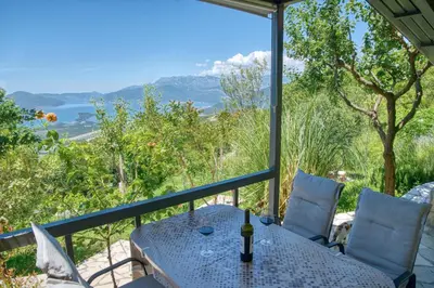 a table and chairs on a balcony with a view of the mountains at Apartment Paradise in Kotor