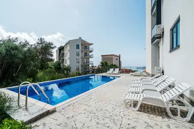 a swimming pool with white lounge chairs next to a building at Olive Tree Apartments by In Property in Becici