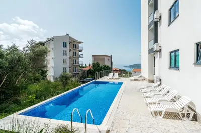 a swimming pool with lounge chairs next to a building at Olive Tree Apartments by In Property in Becici