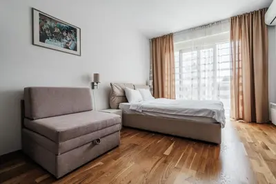 a bedroom with a bed and a chair and a window at Central studio by In Property in Budva