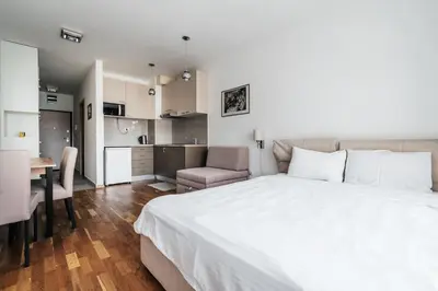 a bedroom with a large white bed and a kitchen at Central studio by In Property in Budva
