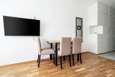 a dining room table with chairs and a flat screen tv at Central studio by In Property in Budva