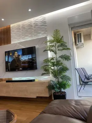 a living room with a tv and a palm tree at Rent a apartment Podgorica in Podgorica