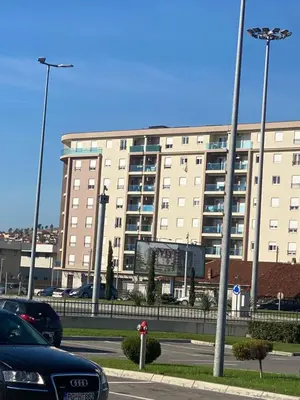a large building with cars parked in a parking lot at Apartman Podgorica in Podgorica