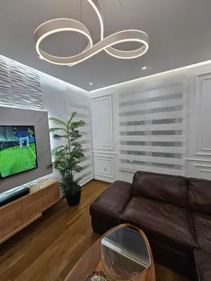 a living room with a brown leather couch and a chandelier at Apartman Podgorica in Podgorica